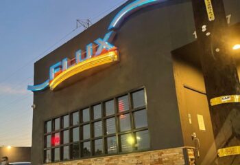 Exterior of Flux Bar, a gay bar. Neon sign with the bar's name. Location for gay travel advice and nightlife.