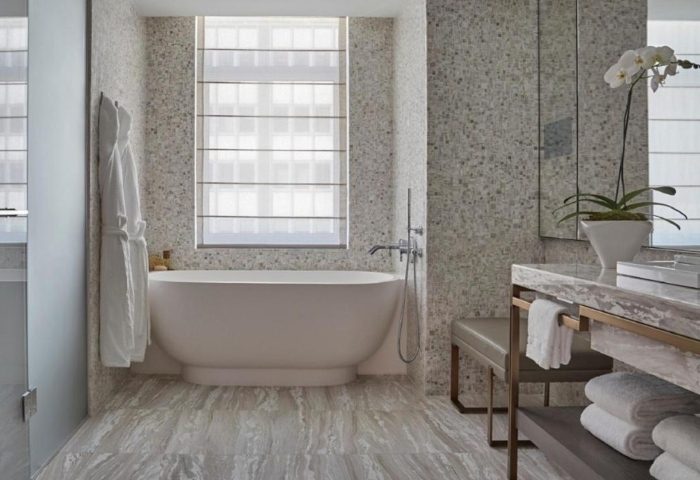 Four Seasons Hotel New York Downtown bathroom. Luxury hotel in East Village gayborhoods. Bathtub, orchid, and marble accents.