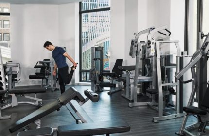 Four Seasons Hotel New York Downtown gym. Man stretching in the wellness hotel near Greenwich Village and East Village gayborhoods.