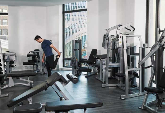 Four Seasons Hotel New York Downtown gym. Man stretching in the wellness hotel near Greenwich Village and East Village gayborhoods.