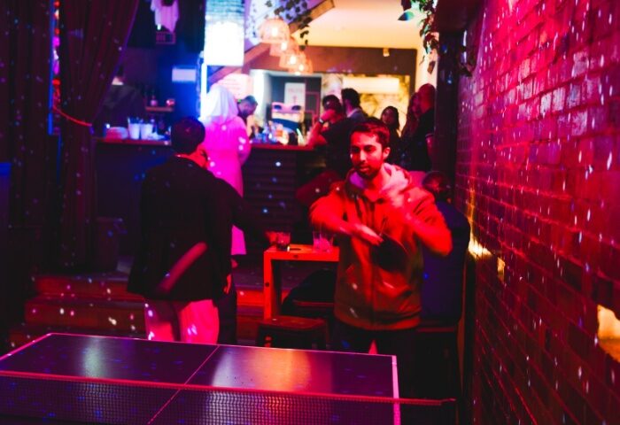 Francesca's Bar, Melbourne. Gay bar scene with men playing ping pong. Red lighting, bar in background, lively atmosphere. Gay travel.
