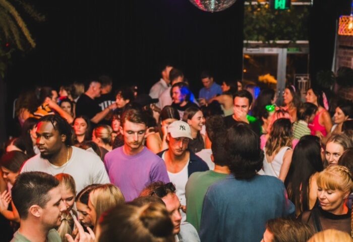 Francesca's Bar Melbourne: A crowded gay bar scene with diverse patrons, disco ball, and lively atmosphere. Gay men travel destination.