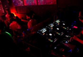 Francesca's Bar Melbourne: A DJ mixes music at a gay bar. The red-lit club features a dance floor and a vibrant atmosphere for gay men travelers.