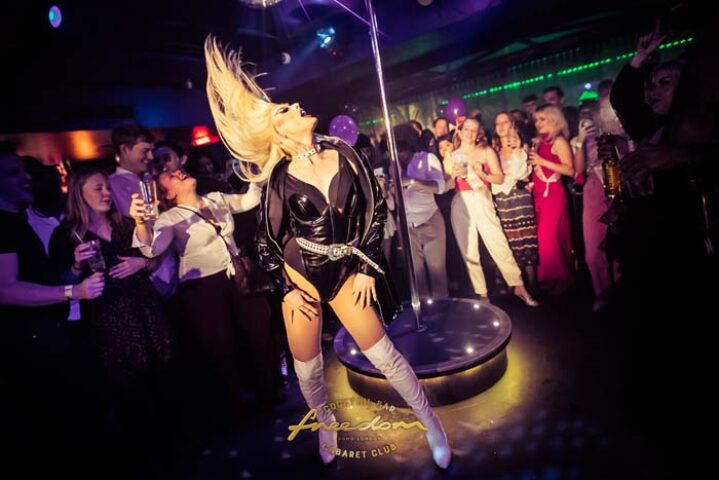 Drag queen performance at Freedom Bar Soho, a popular gay bar in London. The performer is on a pole in front of a crowd.