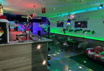 Freedom Club Budapest interior, a gay bar with festive Christmas decorations, bar counter, tables, chairs, and colorful lighting.