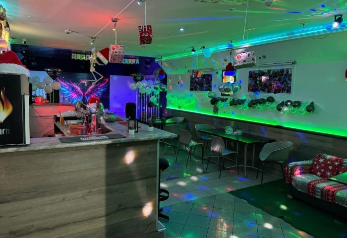 Freedom Club Budapest interior, a gay bar with festive Christmas decorations, bar counter, tables, chairs, and colorful lighting.