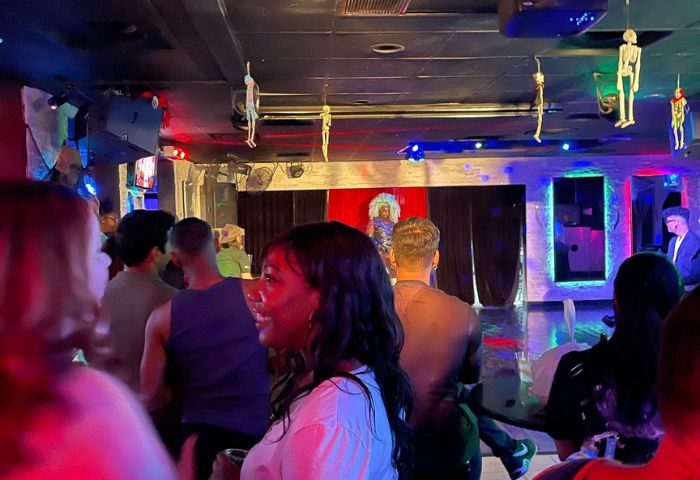 Freezone Gay Bar in Las Vegas: Drag show performance with a diverse crowd. Skeletons hang from ceiling. Nightlife for gay men travel.