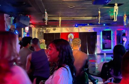 Freezone Gay Bar in Las Vegas: Drag show performance with a diverse crowd. Skeletons hang from ceiling. Nightlife for gay men travel.