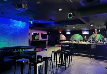Freezone Gay Bar in Las Vegas. Interior view of the bar area with tables, stools, and colorful lighting. A popular gay nightlife spot.