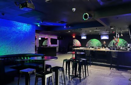 Freezone Gay Bar in Las Vegas. Interior view of the bar area with tables, stools, and colorful lighting. A popular gay nightlife spot.