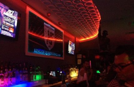 Friend's Tavern in New York City: Gay bar interior with neon lights, TVs, and a lively atmosphere. A popular spot for gay men's travel.