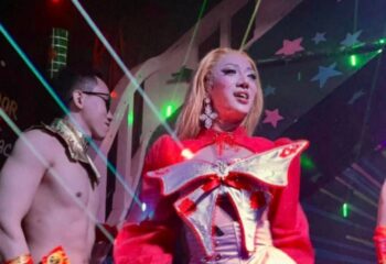 Frolic Bar Ho Chi Minh: Drag queen in red costume, with bare-chested man in gold collar. Gay nightlife in Vietnam.