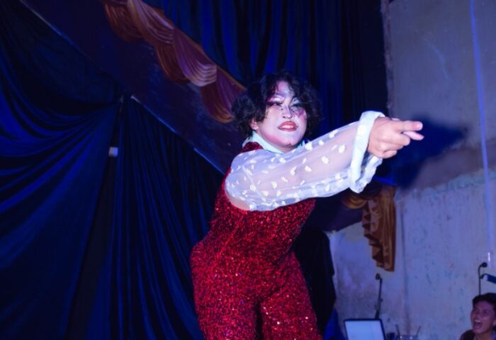 Drag queen performer in Ho Chi Minh City, Vietnam. Red sequin jumpsuit, sheer sleeves. Gay travel advice, nightlife. Full Disclosure.