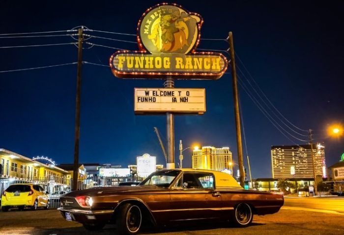Funhog Ranch gay bar in Las Vegas at night. Classic car parked under the neon sign. Gay travel destination for men's vacations.