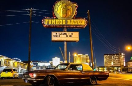 Funhog Ranch gay bar in Las Vegas at night. Classic car parked under the neon sign. Gay travel destination for men's vacations.