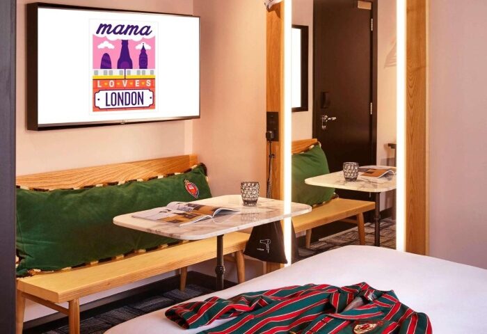 Mama Shelter London Shoreditch room. Fun vibe, gay-friendly hotel near gay saunas. Bench seating, tables, and colorful decor. London travel.