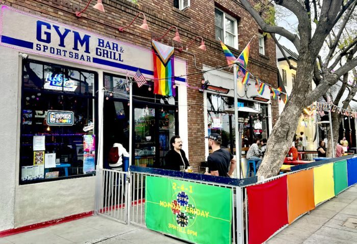 Outdoor view of GYM Sportsbar, a gay bar and grill. Rainbow flags and colorful decor. Gay travel destination. GYM-Sportsbar-Outdoor.jpg
