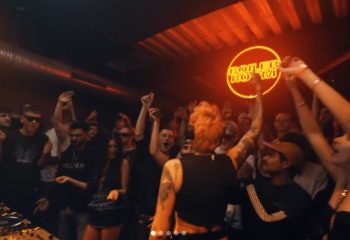 Gay Copenhagen nightlife: A DJ performs at a Boiler Room event in CPH. The crowd is dancing, hands in the air, enjoying the music.