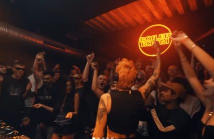 Gay Copenhagen nightlife: A DJ performs at a Boiler Room event in CPH. The crowd is dancing, hands in the air, enjoying the music.