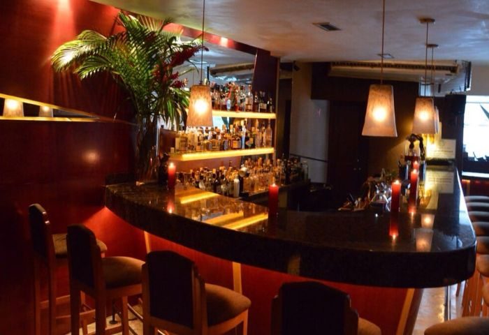 Garbo Piano Bar, a gay-friendly live music venue in Puerto Vallarta. Features a bar with stools, candles, and a shelf of liquor bottles.