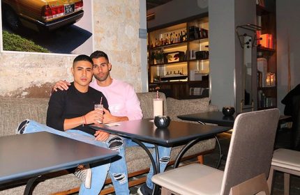 Gay couple at Hôtel Jules & Jim, a gay-adults-only hotel in Paris. Two men sit at a table, drinks in hand, enjoying the hotel's ambiance.