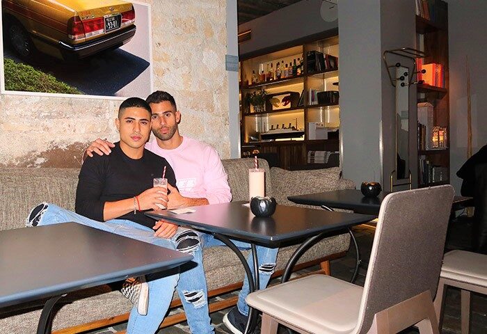 Gay couple at Hôtel Jules & Jim, a gay-adults-only hotel in Paris. Two men sit at a table, drinks in hand, enjoying the hotel's ambiance.