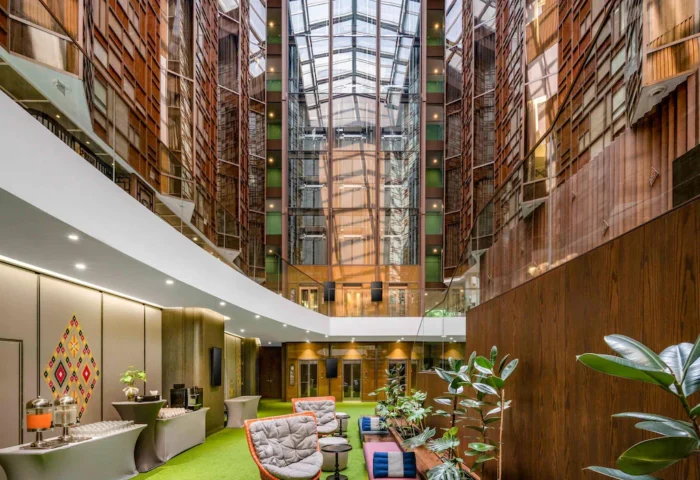 Ibis Styles Bangkok Silom lobby interior. Stylish, budget-friendly gay hotel in Silom, Thailand. Modern design with plants and glass roof.