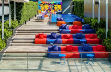 Ibis Styles Bangkok Silom's stylish pool area. Colorful seating tiers, lush greenery, and a vibrant mural create a gay-friendly, budget-chic vibe.