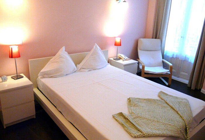 Hostal Pizarro room, a gay-friendly hostel near Madrid's gay bars in Chueca. Features a double bed, pink walls, and a cozy chair.