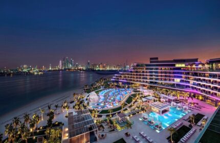W Dubai - The Palm, a gay-friendly hotel at night. Pools, beach, and city skyline views. A luxury travel destination for gay men.