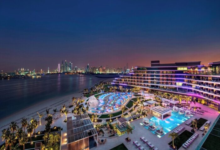W Dubai - The Palm, a gay-friendly hotel at night. Pools, beach, and city skyline views. A luxury travel destination for gay men.