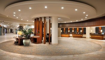 Sheraton Waikiki Beach Resort lobby. Gay-friendly hotel with a circular design, wooden accents, and reception desks. Great for gay travel.