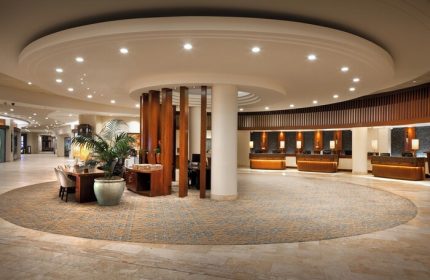 Sheraton Waikiki Beach Resort lobby. Gay-friendly hotel with a circular design, wooden accents, and reception desks. Great for gay travel.