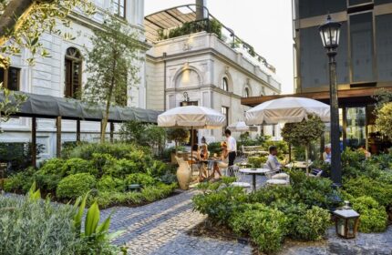 Soho House Istanbul's gay-friendly hotel garden. Outdoor seating, umbrellas, and lush greenery create a relaxing atmosphere. Ideal for gay travelers.