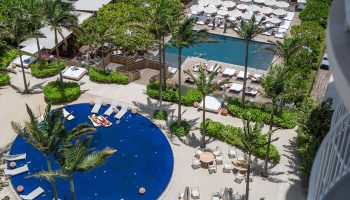 Hilton Vacation Club The Modern Honolulu: Aerial view of a gay-friendly hotel's pools, palm trees, lounge chairs, and umbrellas.