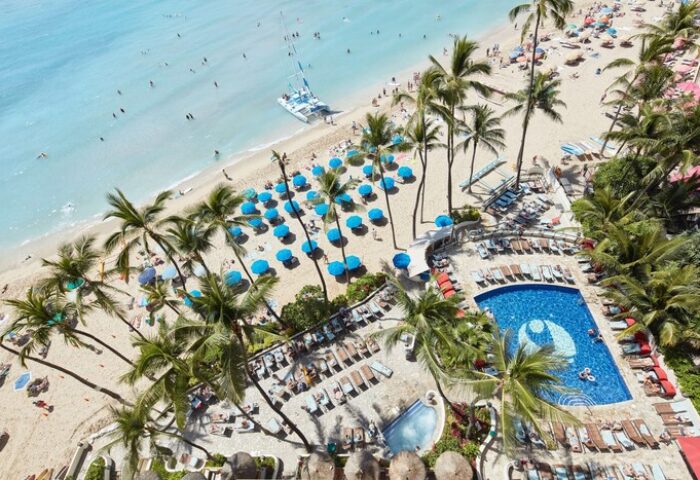 Outrigger Waikiki Beach Resort aerial view. Gay-friendly hotel with pool, beach, and palm trees. Perfect for gay men's travel to Waikiki.