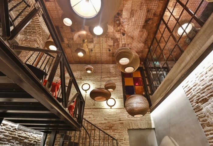 Hotel The Public interior. Gay-friendly hotel's architectural details: exposed brick, metal staircase, and decorative lighting fixtures.