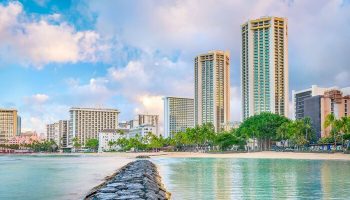 Hyatt Regency Waikiki Beach Resort and Spa view. Gay-friendly hotel on Waikiki Beach, Hawaii. Palm trees, ocean, and city skyline.