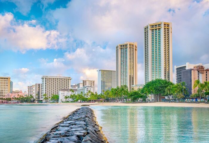 Hyatt Regency Waikiki Beach Resort and Spa view. Gay-friendly hotel on Waikiki Beach, Hawaii. Palm trees, ocean, and city skyline.