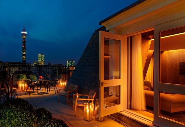 London EDITION gay-friendly hotel room with terrace at night. City view with the BT Tower. Romantic setting with candles.