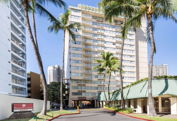 Ramada Plaza by Wyndham Waikiki, a gay-friendly hotel. Exterior view of the hotel with palm trees. Perfect for gay men travel in Waikiki.