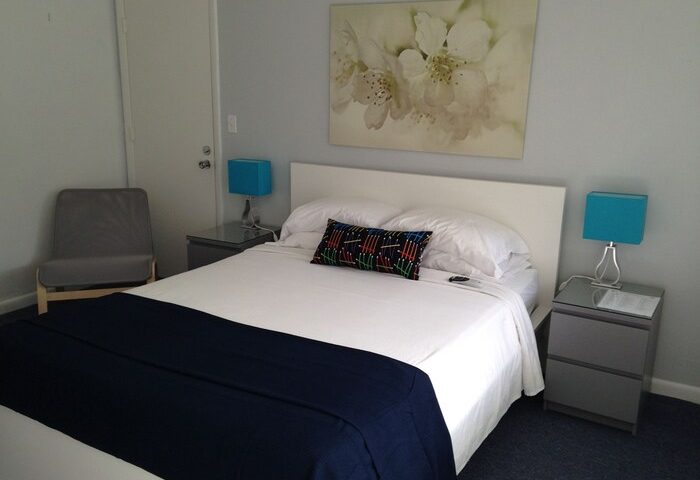 Cheston House guestroom. All-male clothing optional gay-friendly hotel bedroom with bed, chair, & nightstands. Gay travel lodging.