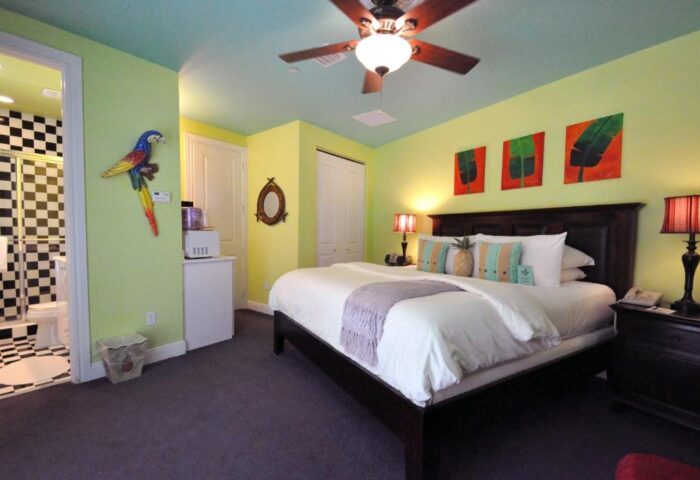 Pineapple Point Guesthouse room. Gay-friendly hotel bedroom with parrot decor, tropical art, and a pineapple pillow. Gay men's resort.