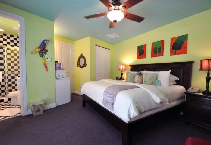 Pineapple Point Guesthouse room. Gay-friendly hotel bedroom with parrot decor, tropical art, and a pineapple pillow. Gay men's resort.