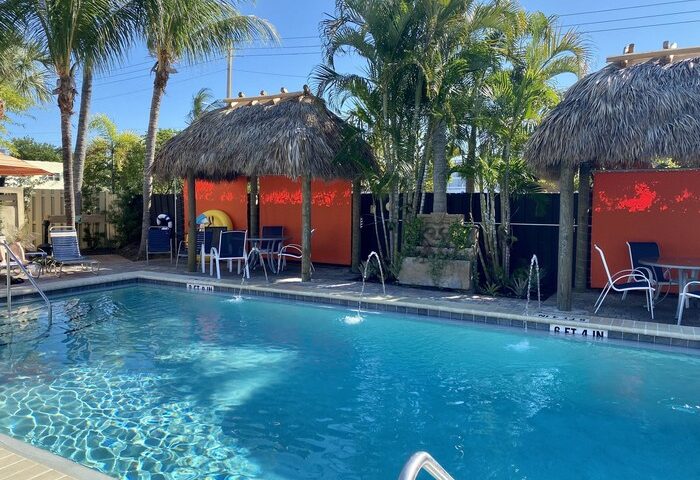 Pool at The Cabanas Guesthouse & Spa, a gay men's resort. Tropical cabanas, palm trees, and clear blue water create a relaxing vibe. Gay-friendly hotel.