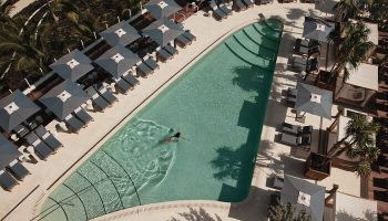 Four Seasons Hotel and Residences Fort Lauderdale pool. Gay-friendly hotel with swimmer, lounge chairs, and umbrellas. Aerial view.