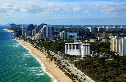 Sonesta Fort Lauderdale Beach aerial view. Gay-friendly hotel on the beach with palm trees, ocean, and city skyline. Great for gay men's travel.