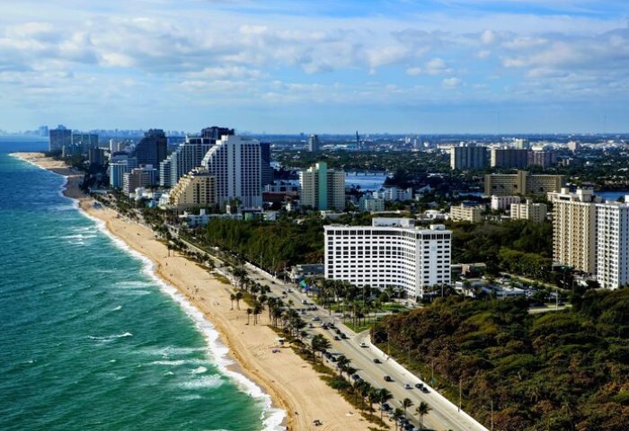 Sonesta Fort Lauderdale Beach aerial view. Gay-friendly hotel on the beach with palm trees, ocean, and city skyline. Great for gay men's travel.