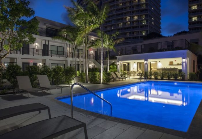 Elita Hotel pool at night. Gay-friendly hotel with lounge chairs and palm trees. Modern architecture, ideal for gay men's travel. Relaxing vacation.