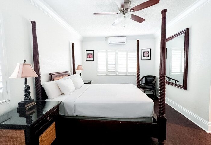 La Casa Hotel gay-friendly room. Four-poster bed, white linens, ceiling fan, and dark wood floors. A comfortable stay for gay travelers.
